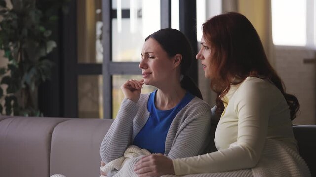 Middle-aged woman comforting and hugging her depressed, crying female friend