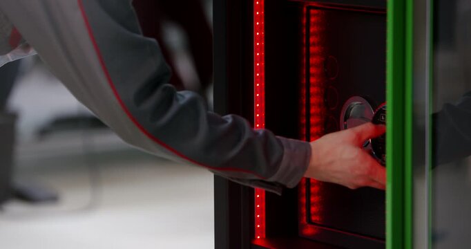 Hand of a person entering a digital code on a numeric keypad lock and turning a safe handle