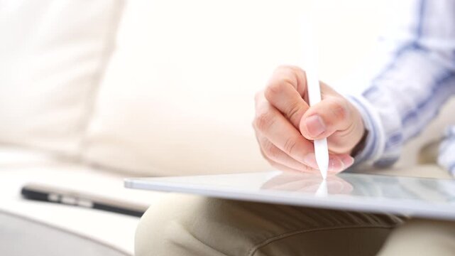 Hand using stylus pen writing on digital tablet, laptop in background. Paperless workflow, Online form completion, Digital checklist, Electronic signature, Business productivity, Modern technology 