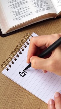 Hand is writing inspirational text "grateful for" in a notebook. Vertical video.