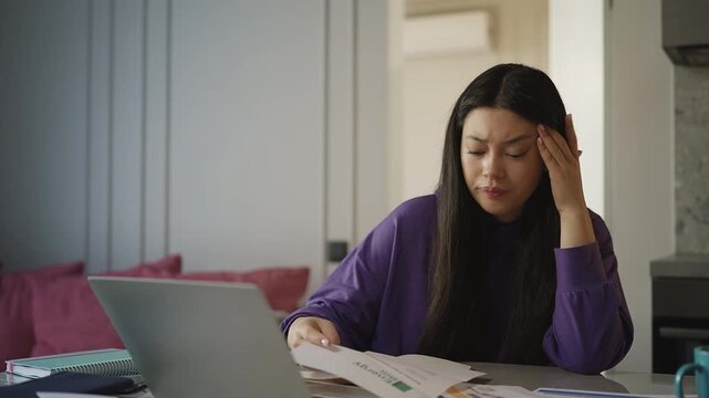 Asian woman shocked while reading an overdue bill, financial debt concept