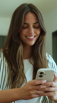 Beautiful young woman with long hair smiling while texting and scrolling on her smartphone, looking happy and connected as she uses the mobile app for social media or messaging