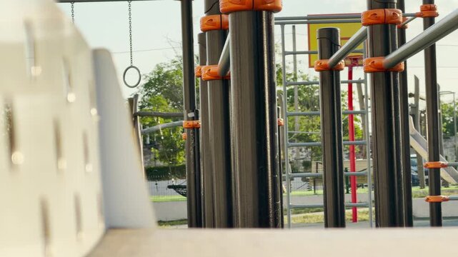 Modern playground equipment stands quietly under the warm sun. The empty sports ground feels peaceful and inviting yet filled with a lonely nostalgia.