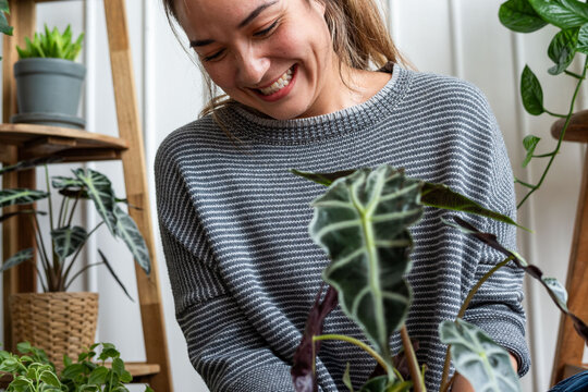 Joyful woman tending houseplants indoors.