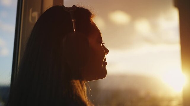 Relaxed woman listening to music through headphones while looking out the window