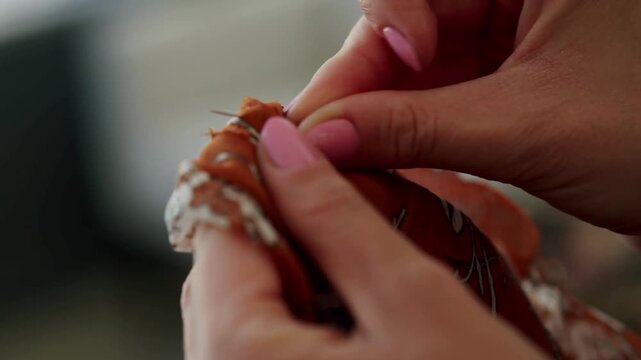 Hands sewing leather material with needle and thread in crafting process