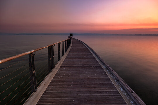 View of Albany Town Jetty at sunset with a wooden walkway extending into the calm water under a colorful sky in Albany, Western Australia, Australia.