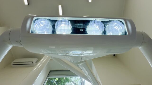 A bright medical lamp glows intensely from the ceiling of a clean, quiet clinic. This powerful light creates a tense but reassuring atmosphere.
