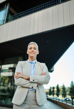 Portrait of a young  businesswoman woman walking down the street, posing and looking at camera, surrounded by moder corporate office buildings