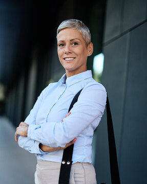 Portrait of a young businesswoman woman walking down the street, surrounded by moder corporate office buildings