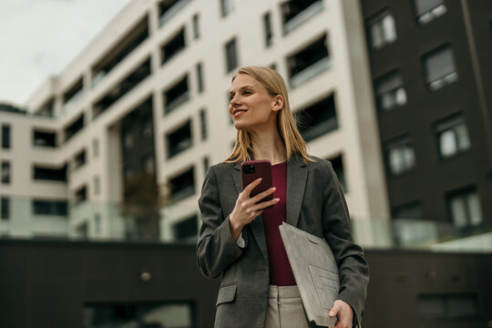 Businesswoman looking ahead holding smartphone and laptop