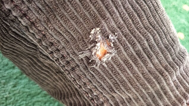 Close-up of torn fabric with visible hole and damaged textile texture