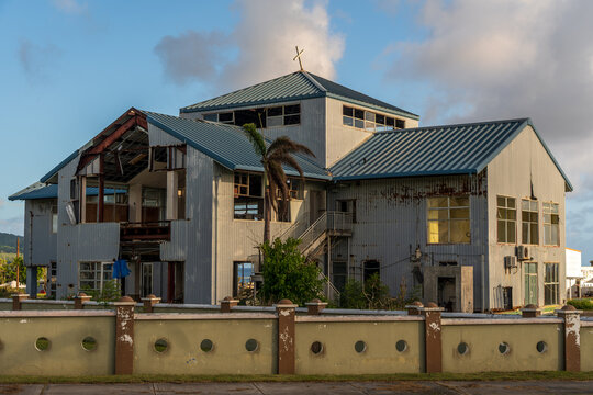 View of the damaged San Jose Catholic Church with exposed structural elements and metal siding in San Jose, Tinian, Northern Mariana Islands.