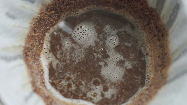 Water pours over coffee grounds in a paper filter during pour over coffee setup. Concept of coffee bloom, manual brewing and fresh coffee preparation