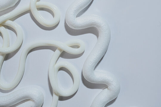 White lotion or cream creating abstract patterns and curves on light background
