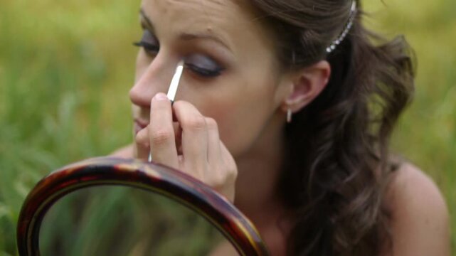 young woman colouring her eyelids
