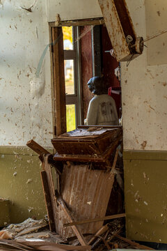 View of the damaged interior of San Jose Catholic Church with debris, peeling paint, and a religious statue visible through a doorway in San Jose, Tinian, Northern Mariana Islands.