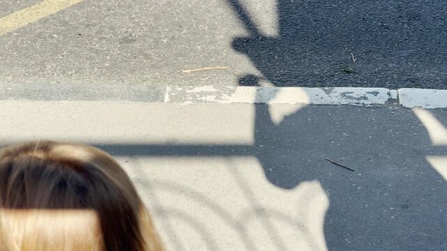 An expectant passenger steps toward an arriving bus at a sunny transit stop in Simferopol, Crimea. The warm shadows bring a hopeful feeling of departure.
