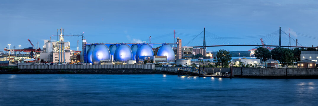 View of the illuminated spherical tanks at Kohlenschiffhafen in the industrial port area with the Kohlbrandbrucke bridge in the background in Hamburg, Hamburg, Germany.