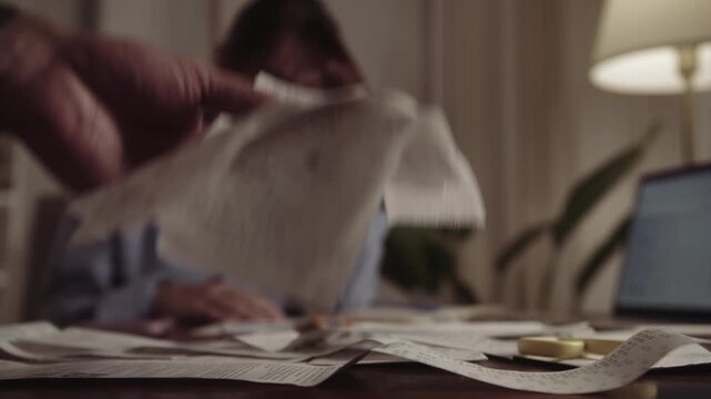 A scene where a married couple is arguing, and the husband waves a stack of receipts from clothing and grocery stores at the camera. The husband is unhappy with his wife's excessive spending. The wife