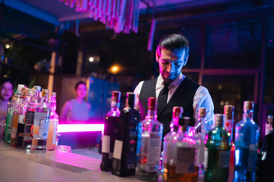 Bartender bar bottle cocktail nightlife neon counter alcohol man bartender preparing drink behind illuminated bar counter with colorful bottle in nightclub lounge