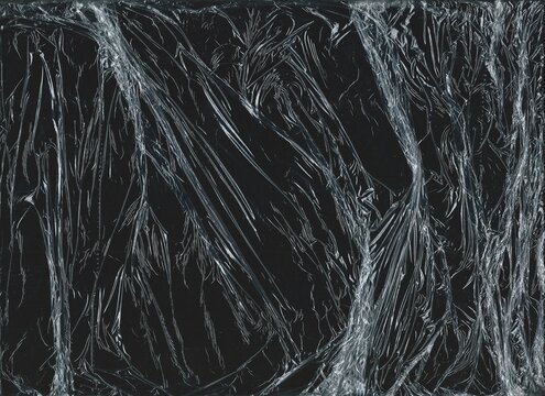 Crumpled plastic overlay texture on a black background. Wrinkled cellophane for grunge cover designs, banners, and backgrounds.