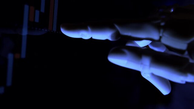 AI humanoid robot arm tracking stock charts on a computer screen. Close-up, low-key footage with shallow depth of field illustrating deep learning.