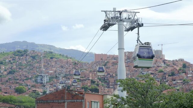 Medell&iacute;n, Antioquia, Colombia &ndash; June 30, 2026 &ndash; Metrocable gondolas transporting passengers above the hillside neighborhoods of Comuna 13, urban public transportation system, recorded at 60fps in 4K