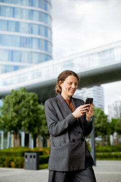 Businesswoman checks phone in urban area during daytime
