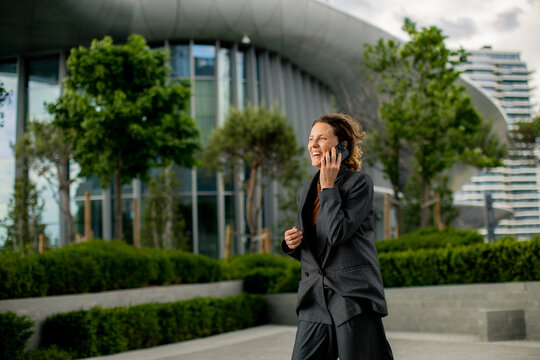 Woman talking on phone while walking in a modern urban setting