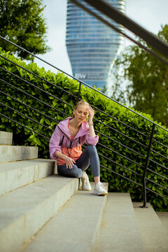 Woman sitting on stairs in a park with a building in the background during the day