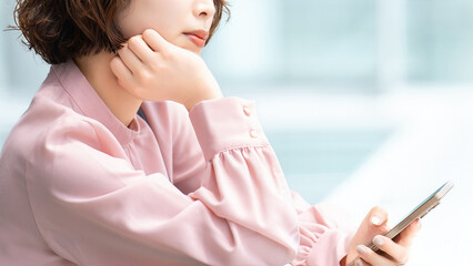 スマートフォンを持って考える女性・ビジネスウーマン, Businesswoman Thinking While Holding a Smartphone © Trickster*