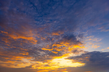 Fototapeta premium Dramatic Golden Sunset Sky with Vibrant Clouds,A breathtaking view of a dramatic golden sunset sky, filled with vibrant orange and yellow clouds scattered across a deep blue twilight atmosphere,