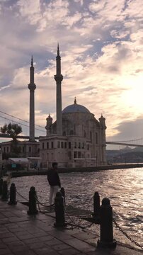 Traveler Walking by Ortakoy Mosque at Sunset in Istanbul Turkey