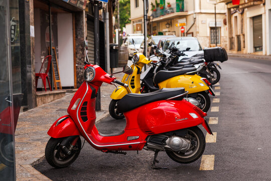 Colorful Vespa motor scooters parked on city street in Soller, Mallorca