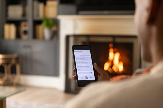 Smartphone screen is displaying readable text while fireplace is casting warm light in living room