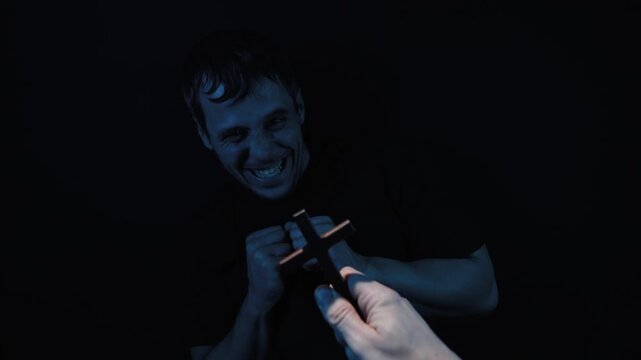 Priest performing exorcism ritual on man who is laughing hysterically but showing deep fear