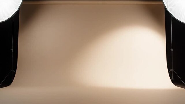 Studio setup with seamless paper backdrop in a warm beige tone illuminated by soft lighting from large softboxes on either side creating a gradient effect