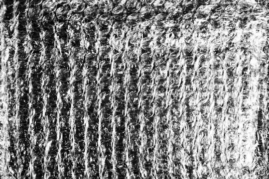 Monochrome macro shot of small-gauge bubble wrap against a black background