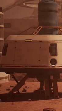 A space exploration vehicle stands on a rocky landscape. The setting shows a dry and dusty terrain with structures in the background. Sunlight illuminates the scene.