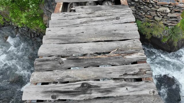 Crossing an old rickety wooden bridge over mountain river