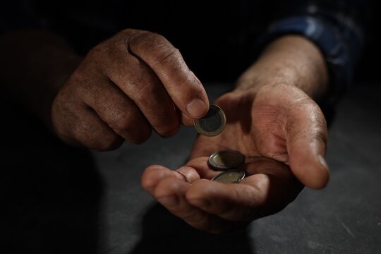 Poverty. Homeless senior man counting coins at table in darkness, closeup