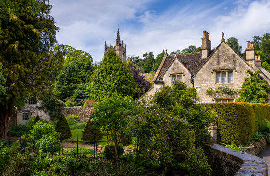 Picturesque village scene featuring St Andrew Church and charming houses in Castle Combe, Wiltshire, England. A popular tourism spot.