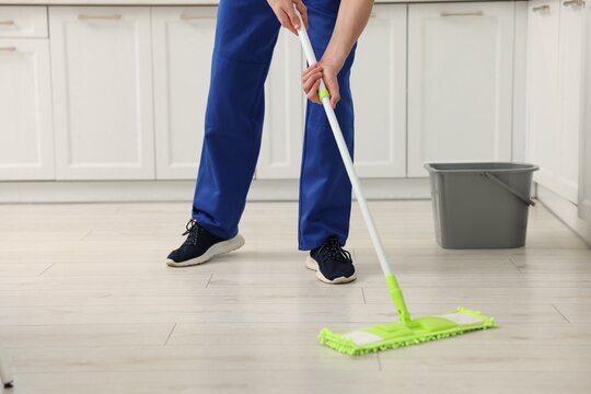 Work for teenagers. Boy cleaning floor with mop in kitchen, closeup