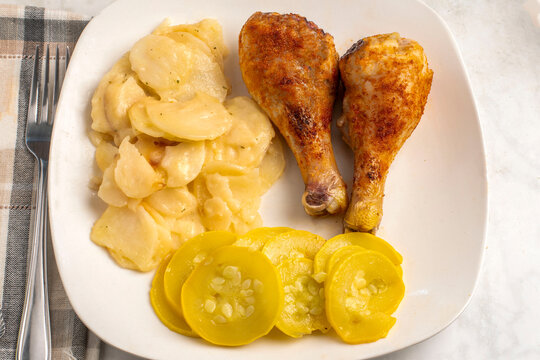 chicken drumsticks  with  a side of scolloped potates