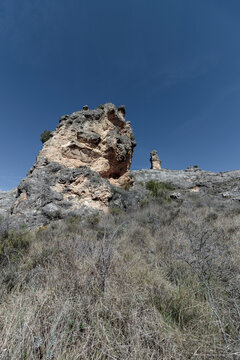 Arid landscape featuring weathered rock formations under blue sky