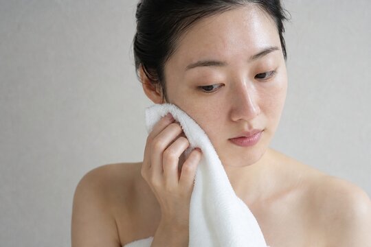 タオルで頬を押さえる女性の皮脂ケア