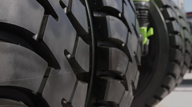 Large agricultural tire tread on tractor wheel in outdoor yard during daytime.