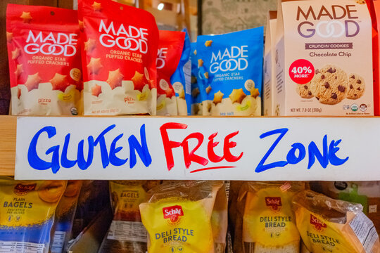 A sign in a grocery store reading gluten free zone in front of a display of cookies.
