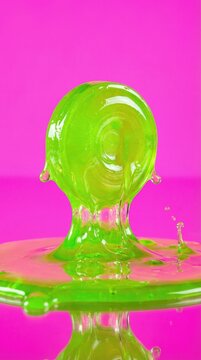 A sculptural splash of neon green slime rises from a surface against a bright pink background. The image conveys a playful, high-contrast, and gooey aesthetic. Great for creative design projects.